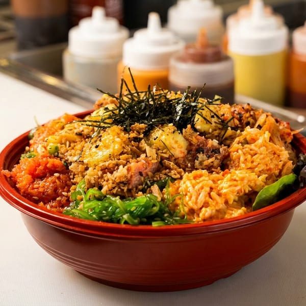 A vibrant poke bowl with various toppings, including seaweed and crispy bits, in a red bowl.